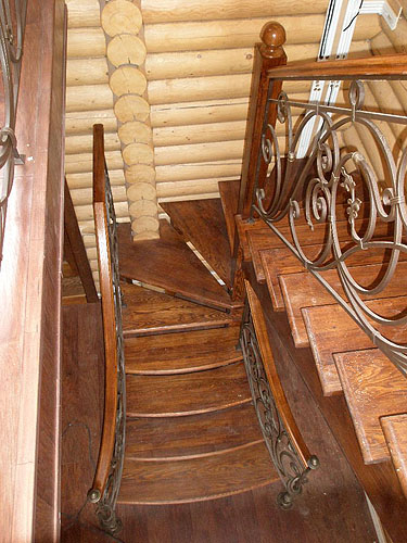 Деревянная лестница с кованым ограждением. Вид сверху на нижную часть
